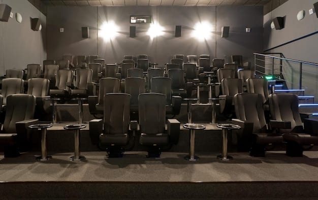 A modern cinema auditorium with comfortable seating, a large screen, and advanced sound system. Moviegoers are shown enjoying the film with popcorn and drinks. The lighting is dim and focused on the screen, creating an immersive viewing experience.