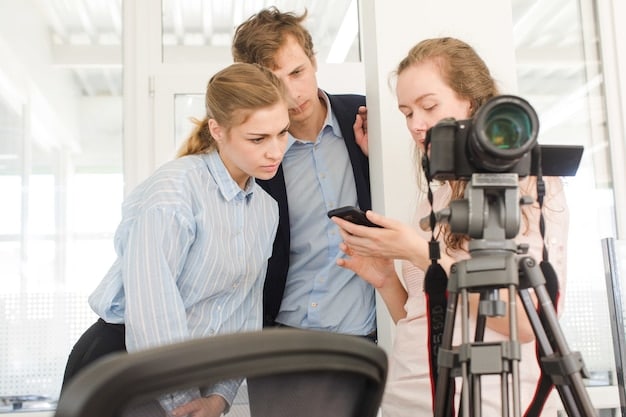 A group of young filmmakers gathered around a monitor, reviewing footage from a recent shoot. They are discussing the scene and brainstorming ideas for improvement. The atmosphere is collaborative and enthusiastic.