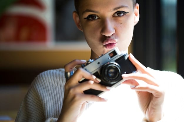 A close-up shot of a student using a professional camera on a film set within a film school. The student is focused, with the camera lens prominent. The background is slightly blurred, showing other crew members and equipment.