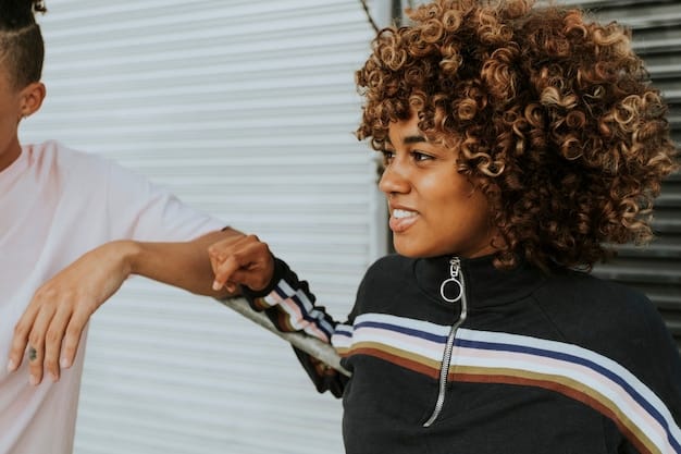 A close-up of a stylist applying hair relaxer to a section of curly hair in a salon. The stylist is wearing gloves and using a brush for precise application, with the focus on the creamy texture of the relaxer and the contrast between the curly and straightened sections.