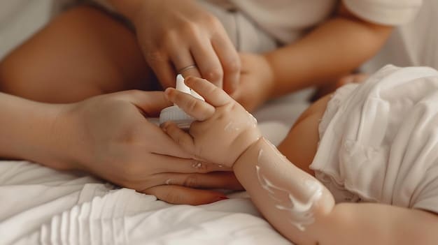 A close-up shot of a mother's hands gently massaging baby oil onto her baby's leg. The focus is on the soft, smooth skin and the nurturing, careful touch.