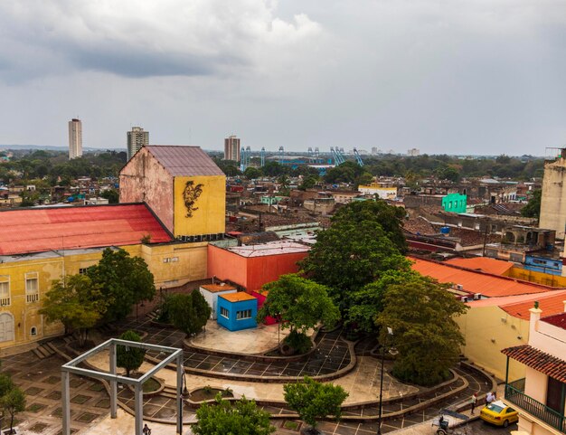 A high-angle shot of a film set in Lagos, Nigeria. The setting includes colorful buildings, bustling street vendors, and a crowd of extras dressed in vibrant traditional Nigerian clothing. The main focus is on the film crew using professional camera equipment to capture a scene.