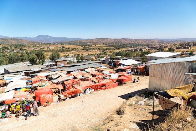 A panoramic view of a vibrant marketplace in a rural Nigerian town, showcasing the cultural richness and diversity of potential filming locations. The scene includes colorful textiles, local vendors, and traditional architecture.